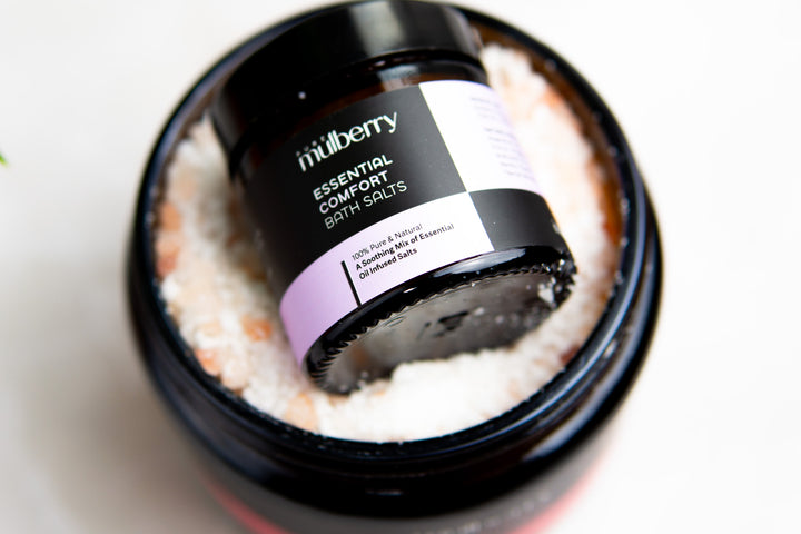 Small jar of white and pink bath salts nestling in a large jar